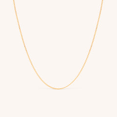 14K solid yellow gold dainty curb chain necklace with a minimalist design, featuring delicate Cuban links. Perfect for layering or wearing solo, this timeless gold chain adds elegance to any look, ideal for daily wear or special occasions.