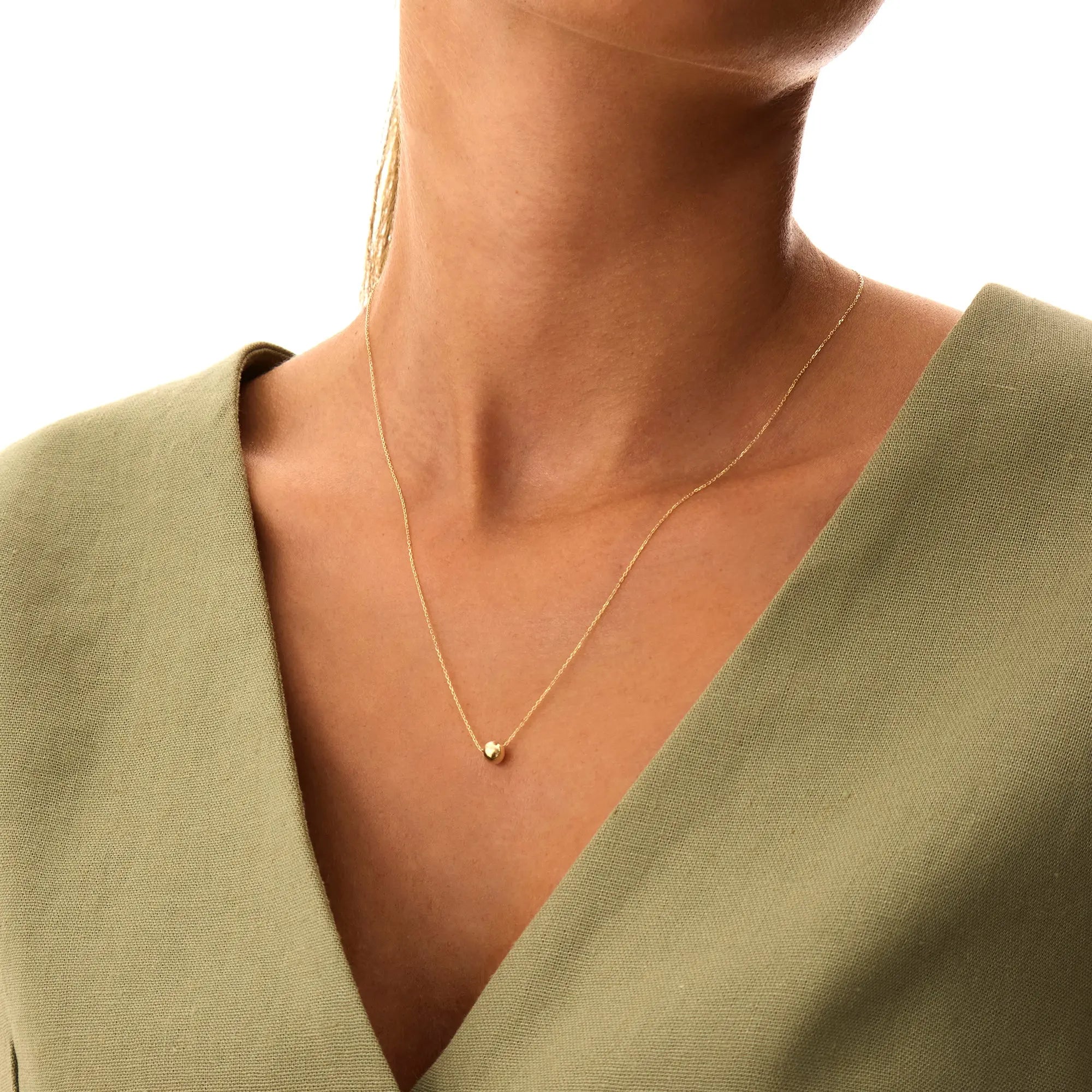 Simple and chic 14K solid gold floating bead necklace. This minimalist design showcases a single gold sphere, adding a touch of elegance to any look.