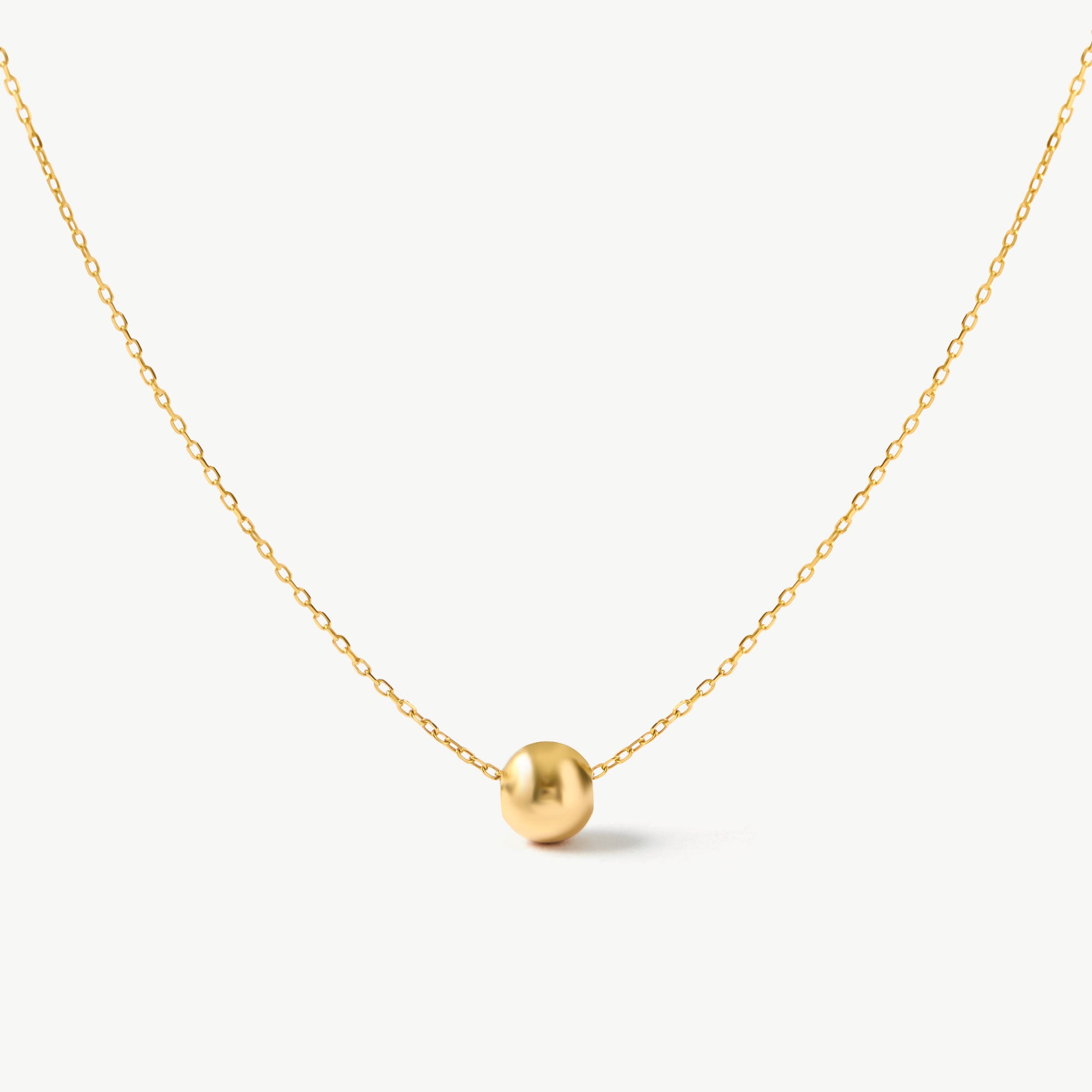 14K real solid yellow gold minimalist necklace featuring a single floating gold bead. A dainty and elegant everyday accessory perfect for layering or wearing alone.