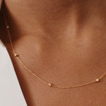 Minimalist 14K yellow gold station necklace with tiny textured beads evenly spaced along the chain. This dainty, delicate piece adds a subtle touch of sophistication, ideal for layering or wearing alone for a simple, elegant look.