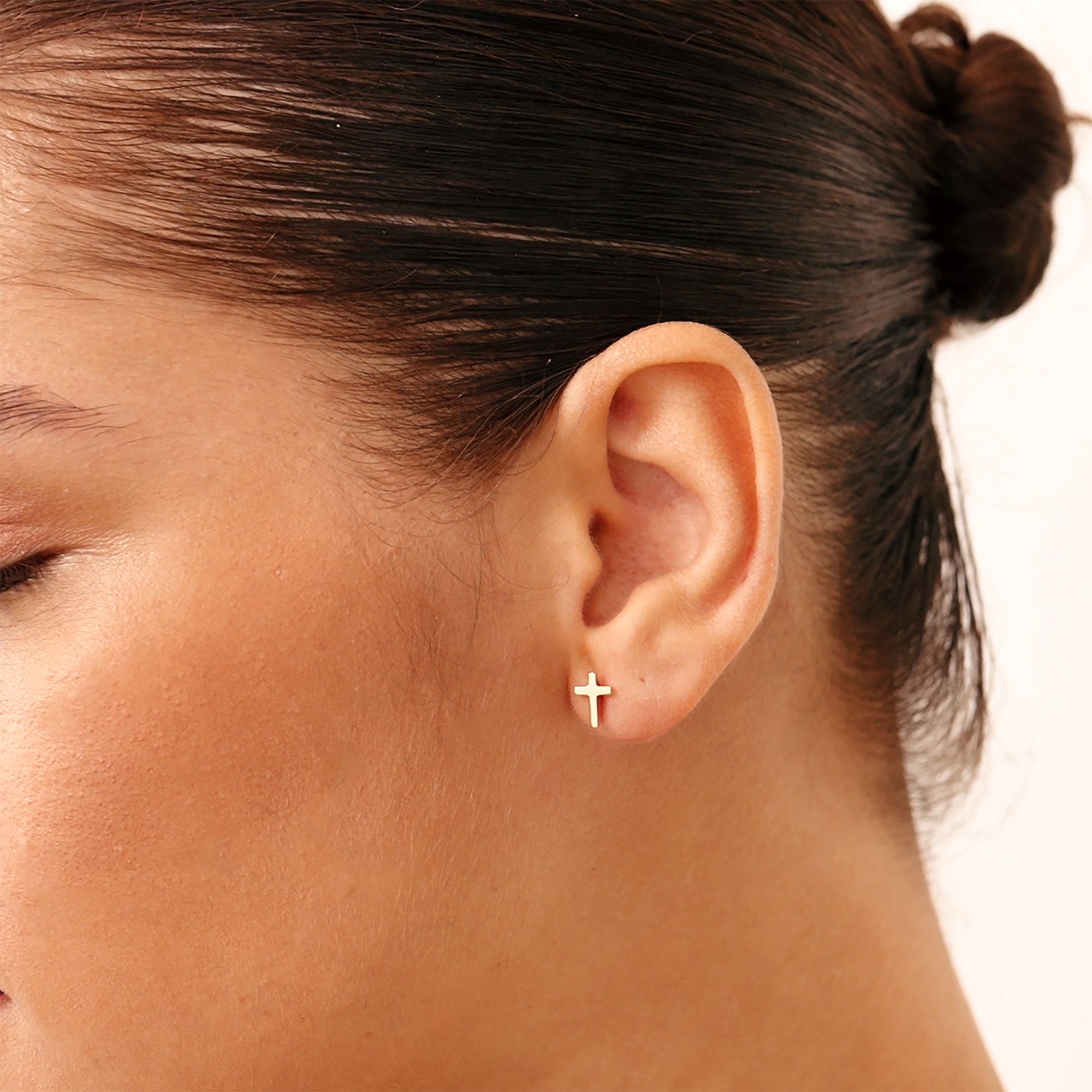 A pair of 14K solid yellow gold dainty cross stud earrings. These minimalist crucifix earrings feature a clean and simple design, ideal for daily wear or as a thoughtful baptism or religious gift, symbolizing faith and devotion.