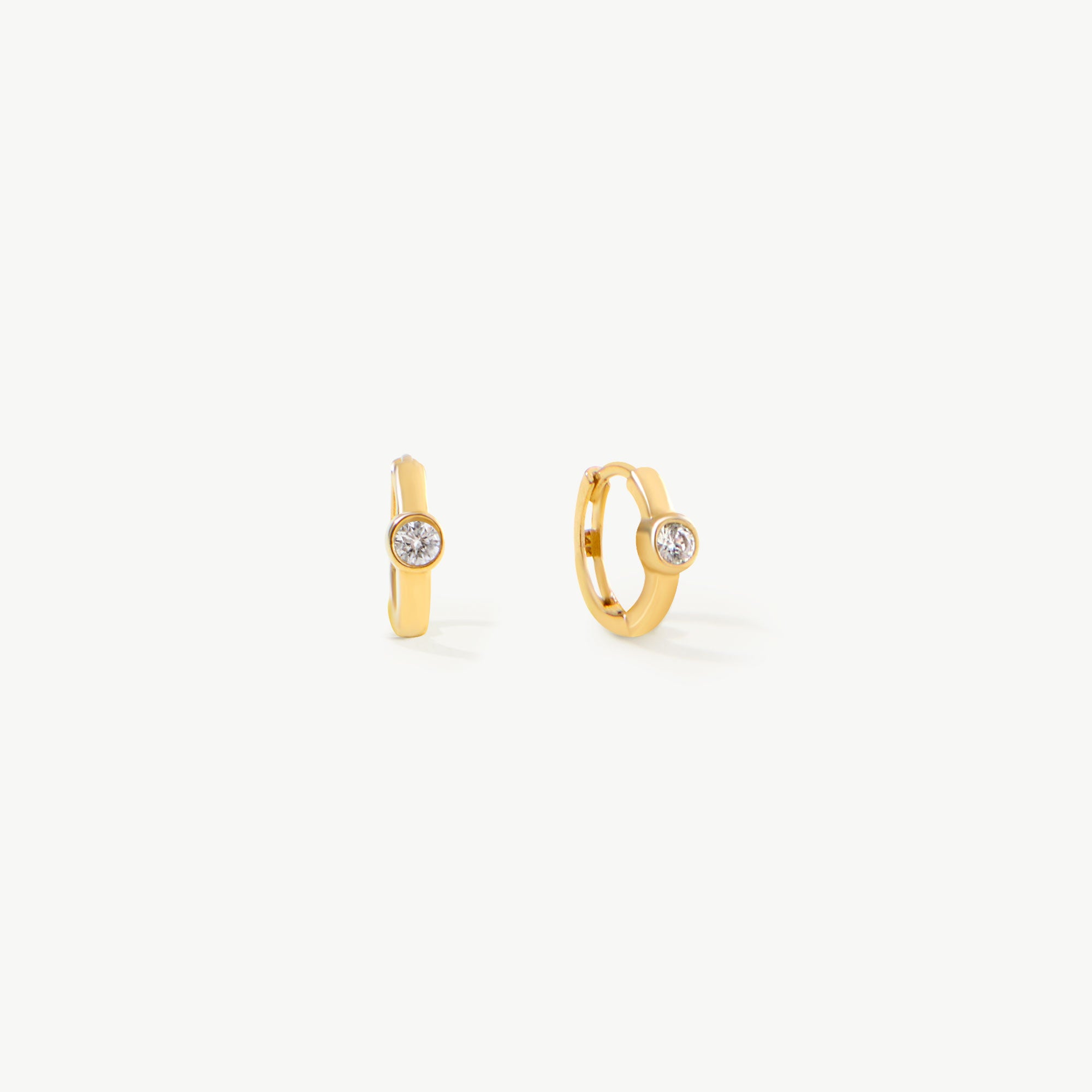 14K real solid yellow gold diamond huggie hoop earrings featuring a minimalist design with a bezel-set round diamond. These dainty small hoops are perfect for everyday wear, adding a subtle yet luxurious touch to any outfit.