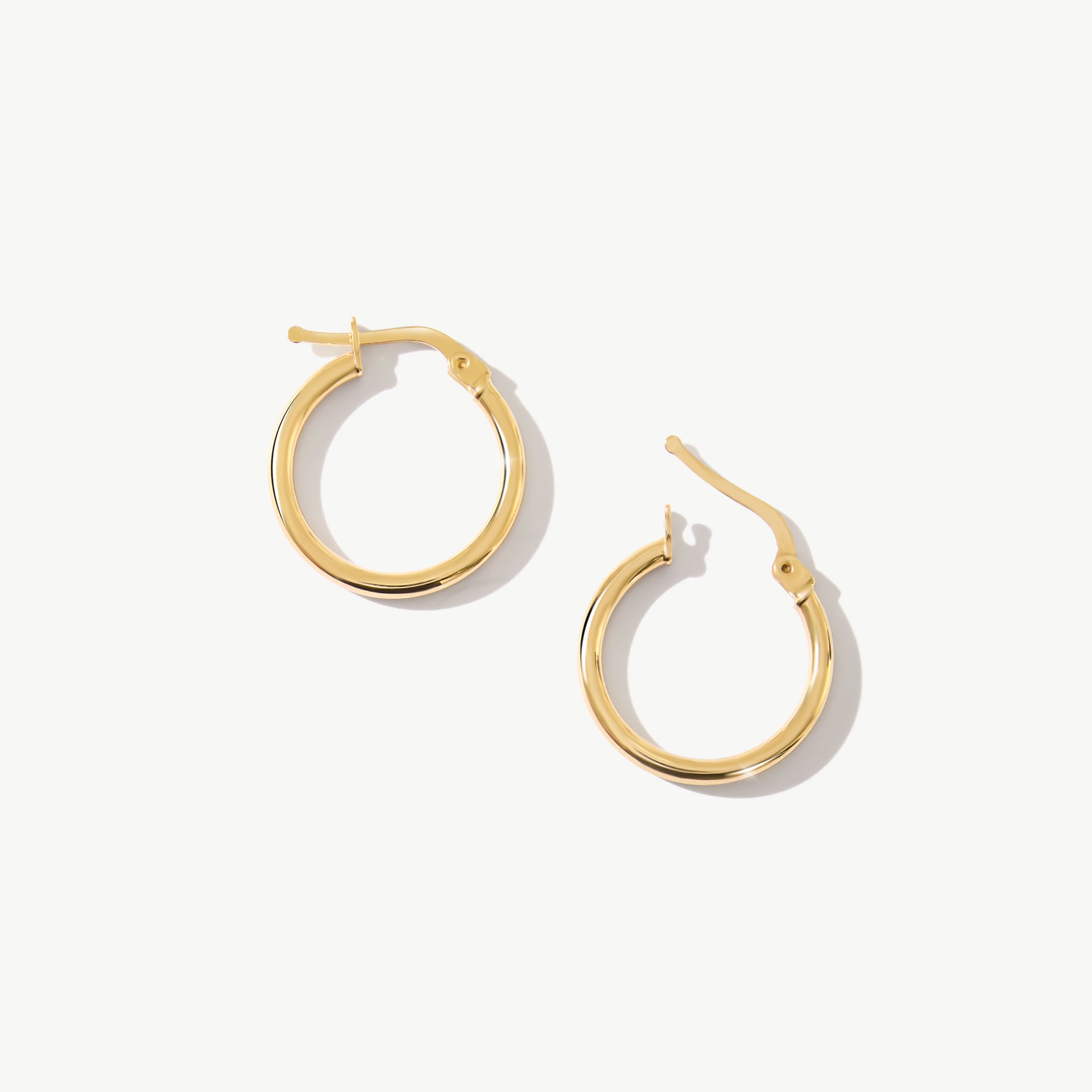 14K real solid yellow gold huggie hoop earrings featuring a sleek and minimalist design. These small, medium-sized hoops offer a polished and refined look, perfect for everyday wear or layering with other jewelry.