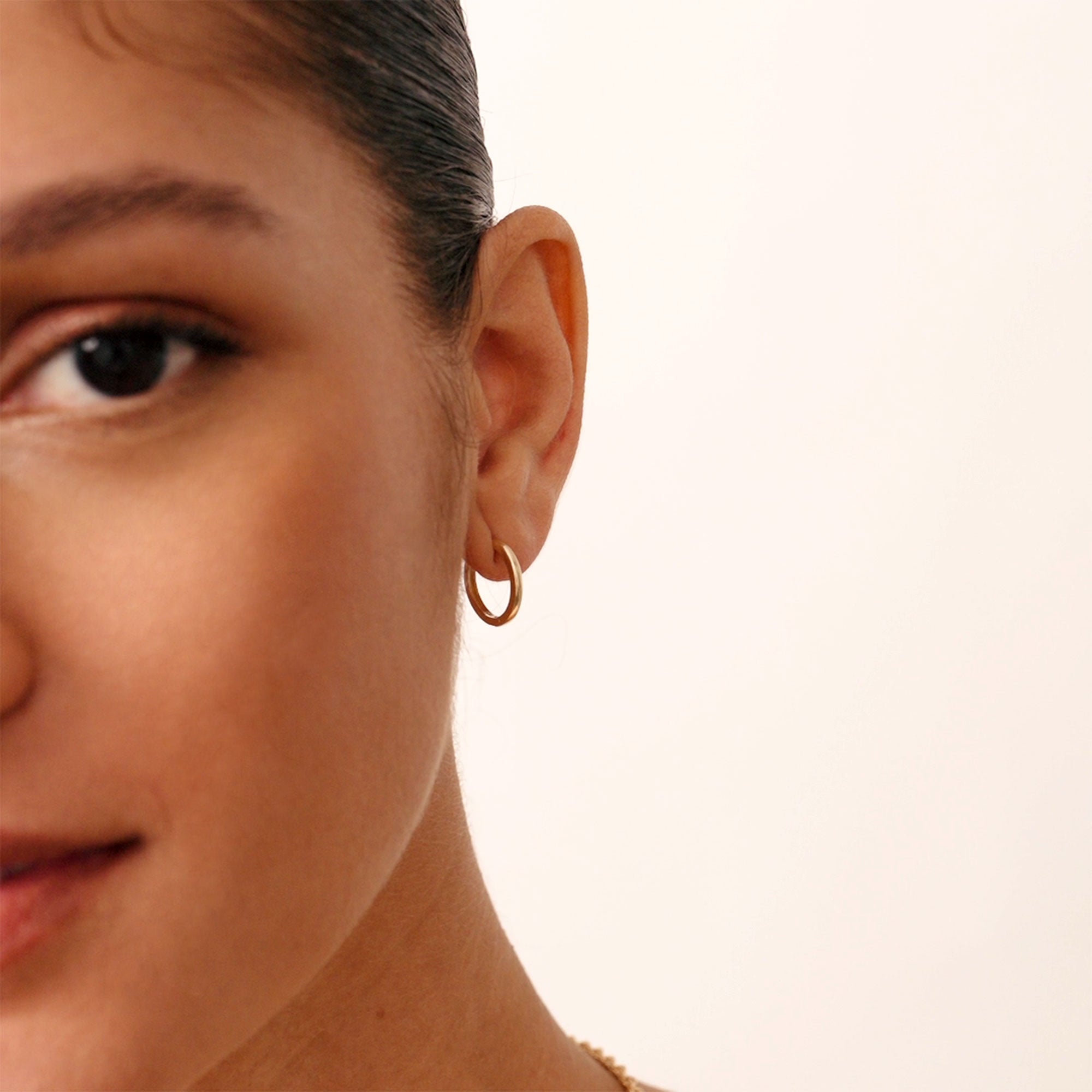 A pair of 14K real solid gold small thick hoop earrings with a sleek, minimalist design, perfect for everyday wear and special occasions, featuring a secure latch-back closure for comfort and style.