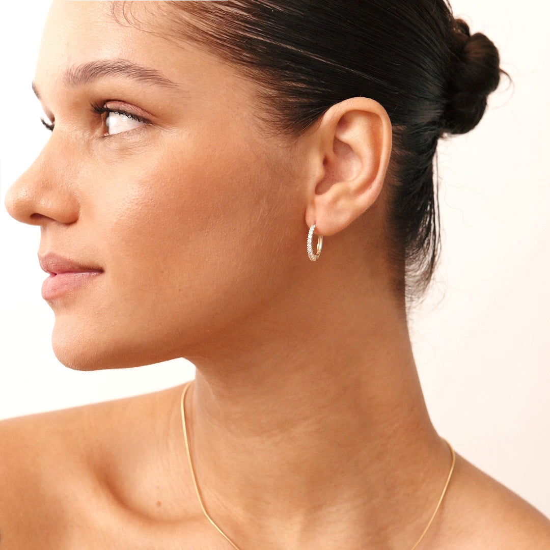 Very small 14K gold hoop earrings featuring diamond accents, combining elegance with comfort for a versatile, timeless look.