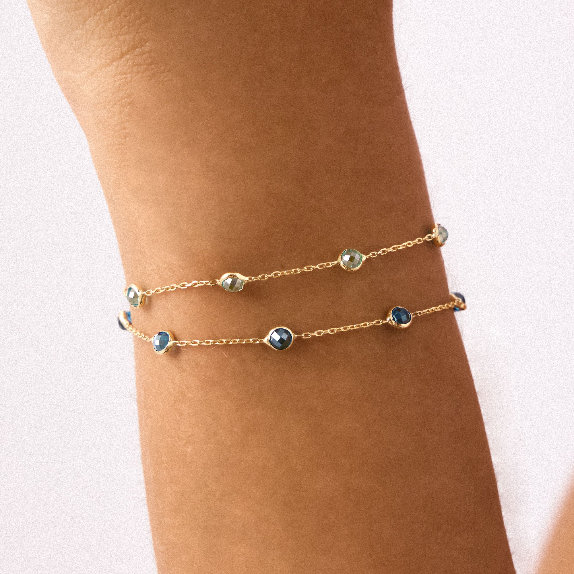 A 14K Real Solid Gold London Blue Topaz Birthstone Station Bracelet featuring deep blue, faceted gemstones set along a fine gold chain, perfect for elegant wear.
