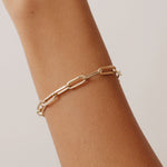 14K solid gold paperclip chain bracelet with elongated links on a wrist. A stylish and modern bracelet perfect for layering or wearing alone, suitable as a gift for her or him for special occasions.