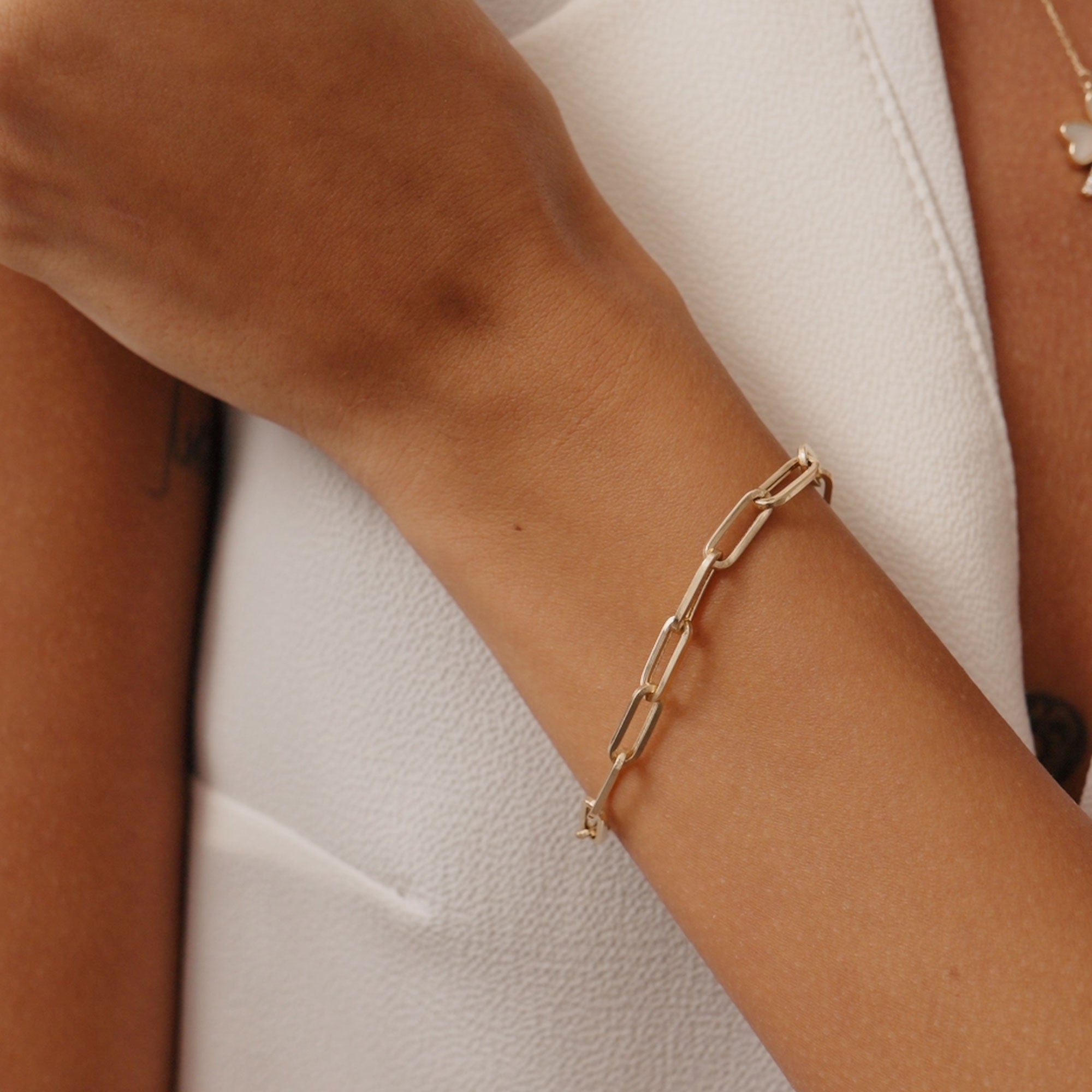 14K solid gold paperclip chain bracelet with elongated links on a wrist. A stylish and modern bracelet perfect for layering or wearing alone, suitable as a gift for her or him for special occasions.