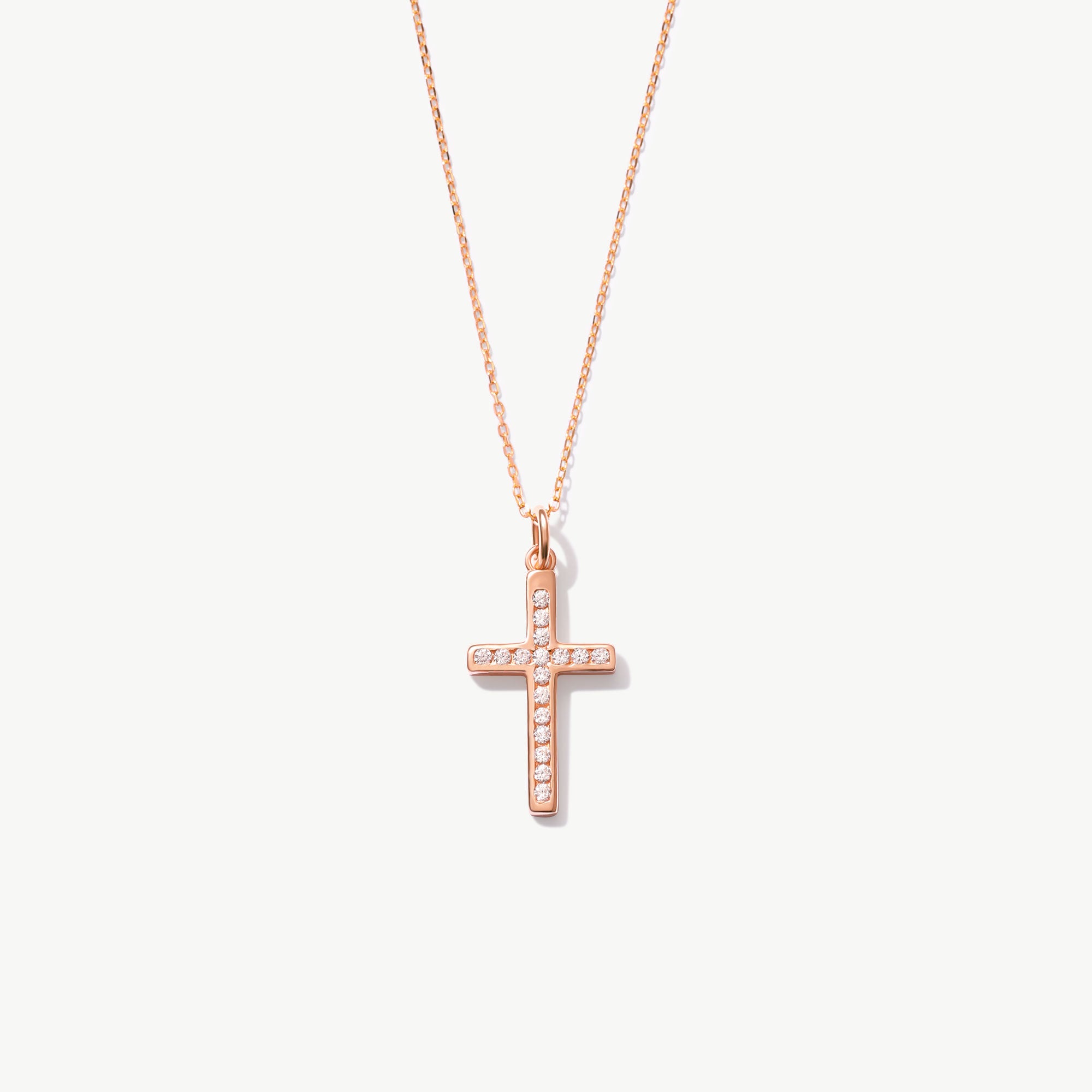 Rose gold cross necklace with diamonds on a white background