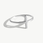 14K solid white gold cross ring photographed on a white background with realistic reflections and shadowing, featuring a minimalist sideways cross design and thin polished band suitable for stacking.