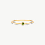 Minimalist 14K solid gold birthstone ring featuring a natural green peridot gemstone in a delicate bezel setting on a thin polished gold band photographed on a white background.