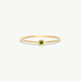 Minimalist 14K solid gold birthstone ring featuring a natural green peridot gemstone in a delicate bezel setting on a thin polished gold band photographed on a white background.