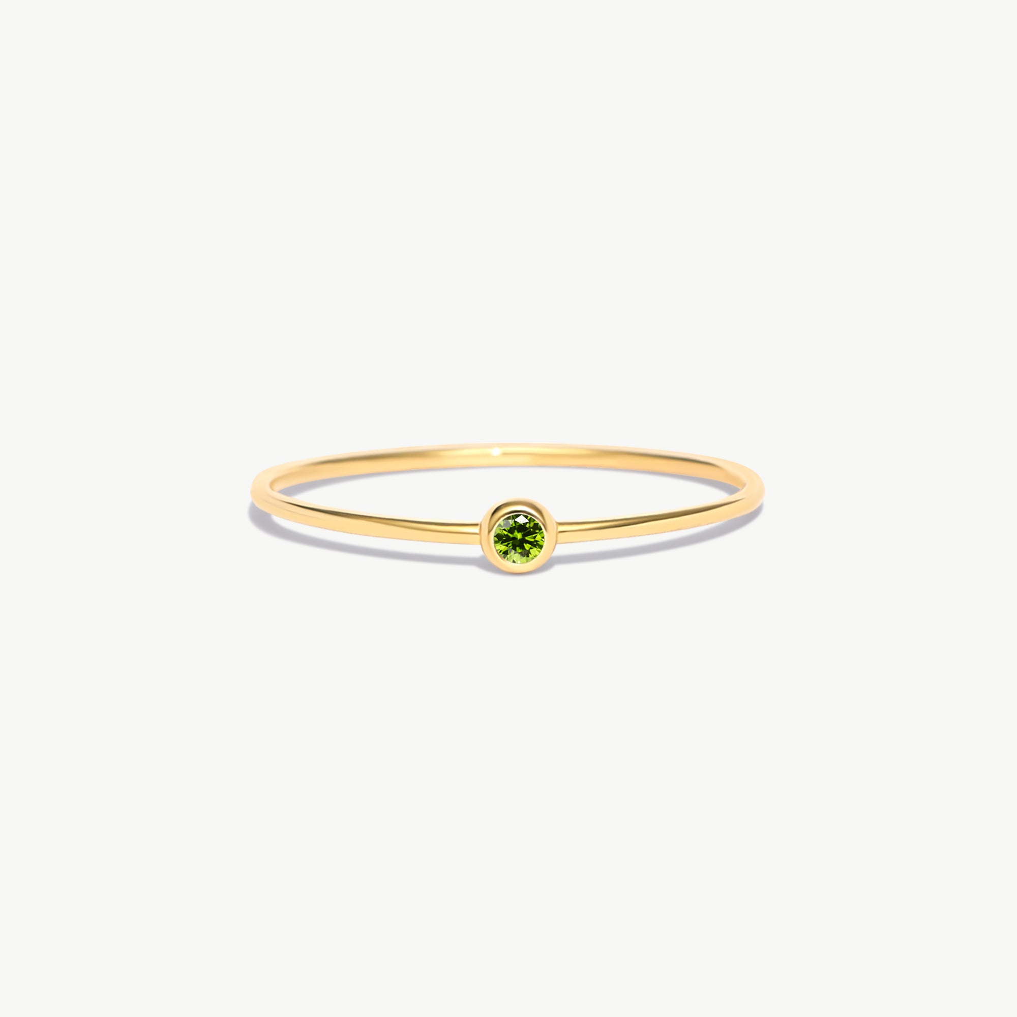Minimalist 14K solid gold birthstone ring featuring a natural green peridot gemstone in a delicate bezel setting on a thin polished gold band photographed on a white background.