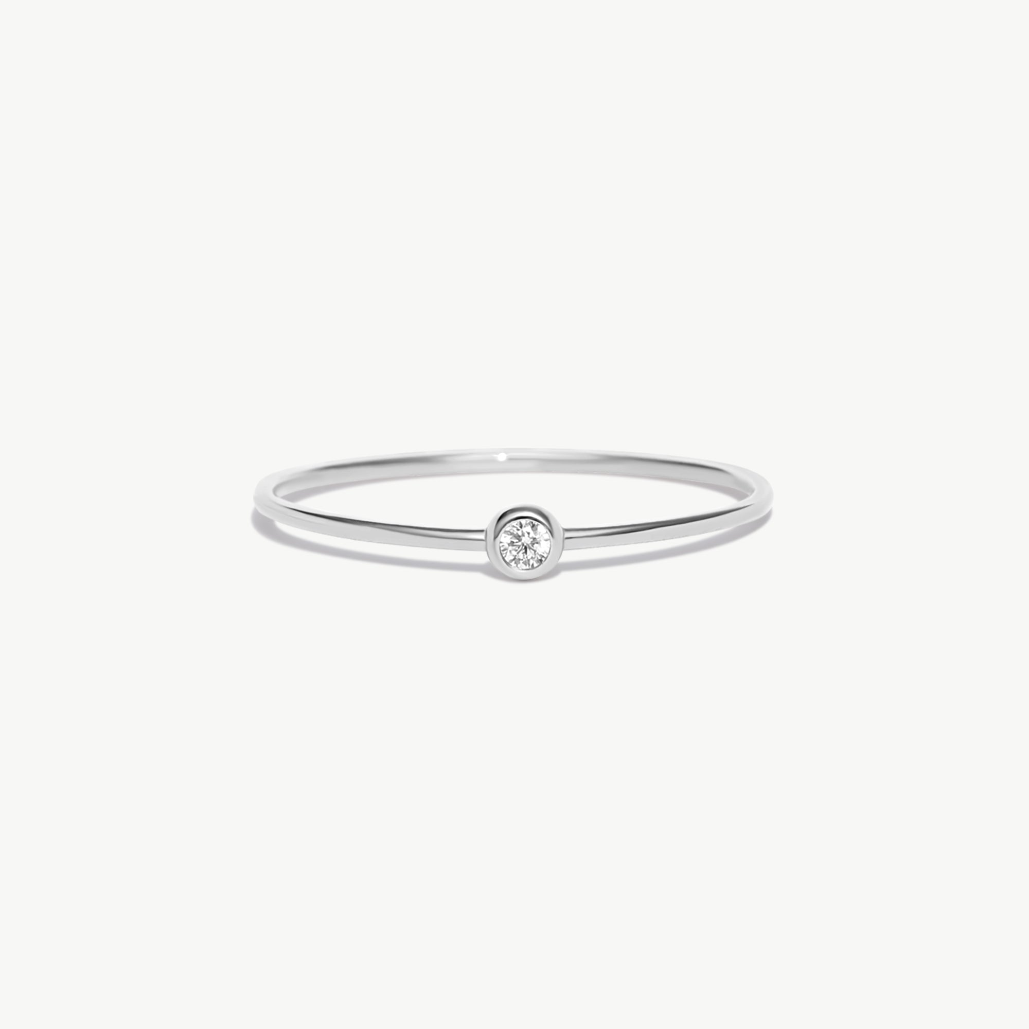 Minimalist white gold birthstone ring featuring a natural diamond center stone in a polished bezel setting on a thin stackable solid gold band.