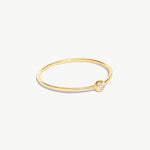 Side-angle product photograph of a delicate 14K solid gold birthstone ring with natural diamond bezel setting and ultra-thin minimalist band design.