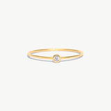 Fine jewelry product image of a delicate 14K solid gold birthstone ring with a natural diamond center stone and polished ultra-thin minimalist band photographed on a white background.