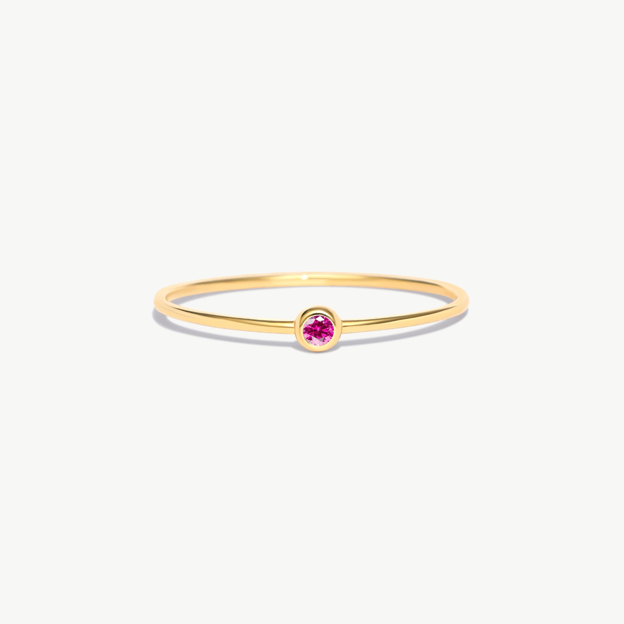 Minimalist 14K solid gold birthstone ring featuring a natural pink tourmaline gemstone in a refined bezel setting with delicate stackable thin band styling.