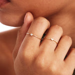 Editorial close-up portrait showing a woman wearing elegant stackable 14K solid gold birthstone rings with natural gemstones and minimalist everyday jewelry styling.