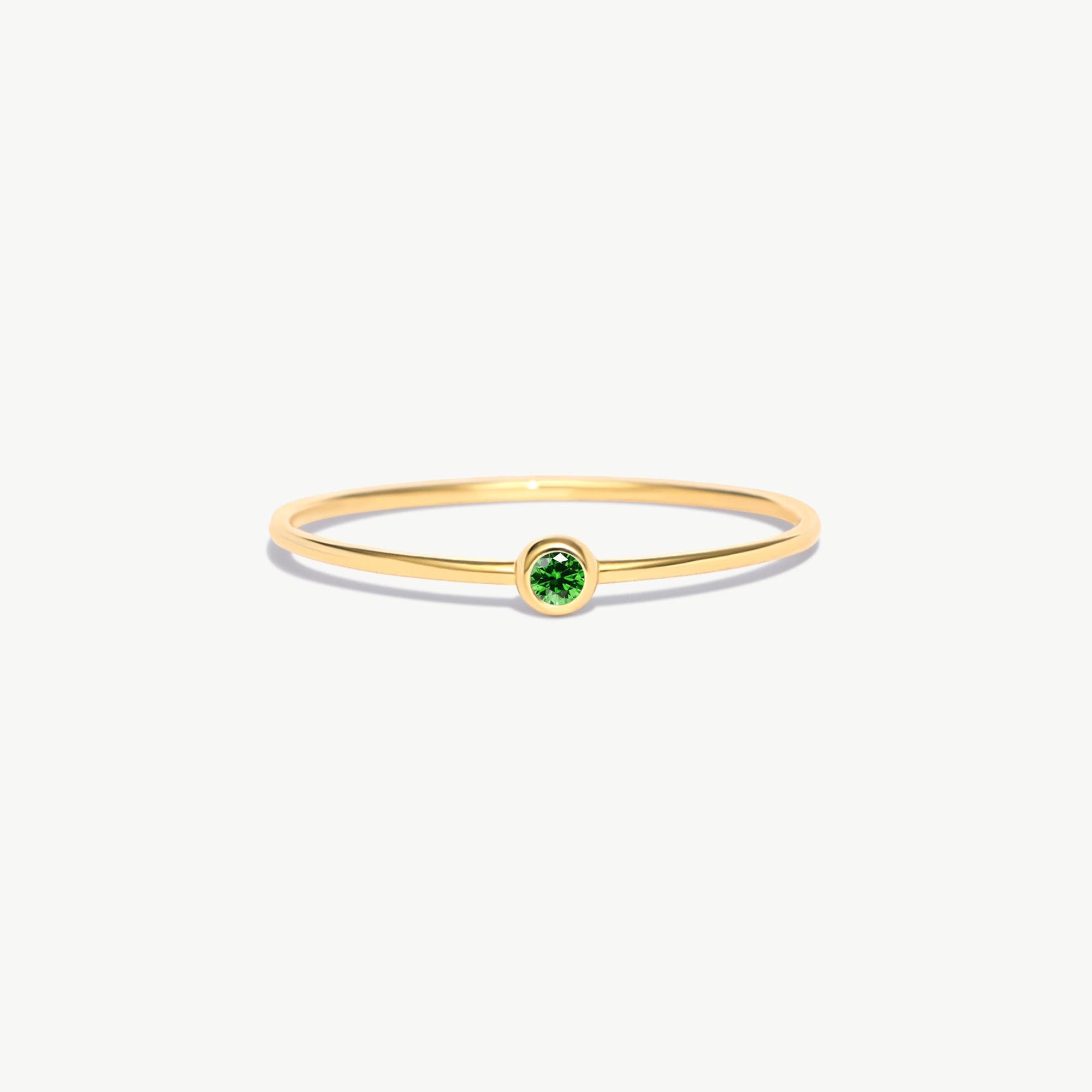 Fine jewelry product image of a minimalist natural emerald birthstone ring crafted from genuine 14K solid gold with delicate thin band proportions photographed on a white background.
