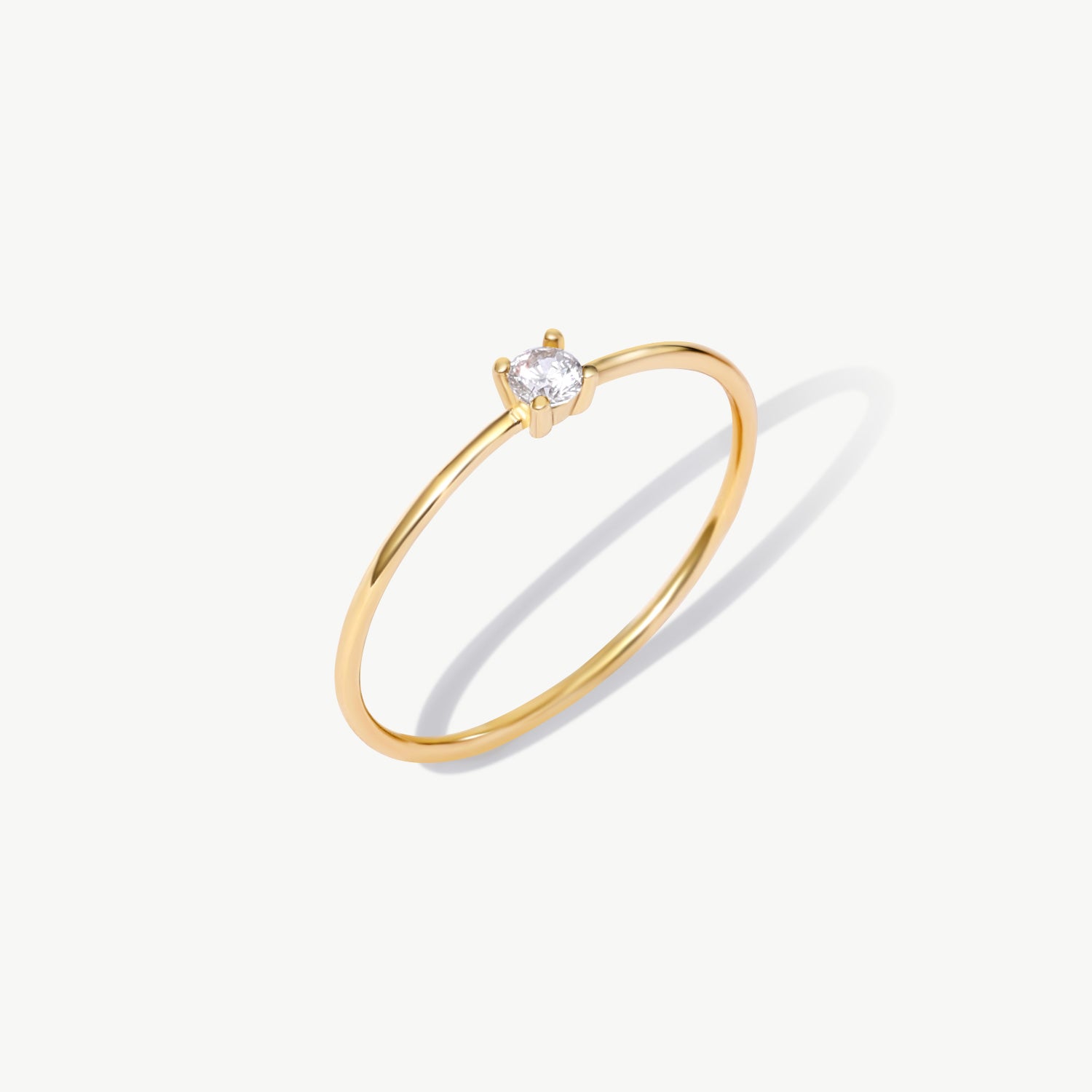 Fine jewelry product image of a dainty 14K solid gold solitaire engagement ring featuring a natural round diamond and slim minimalist band design.