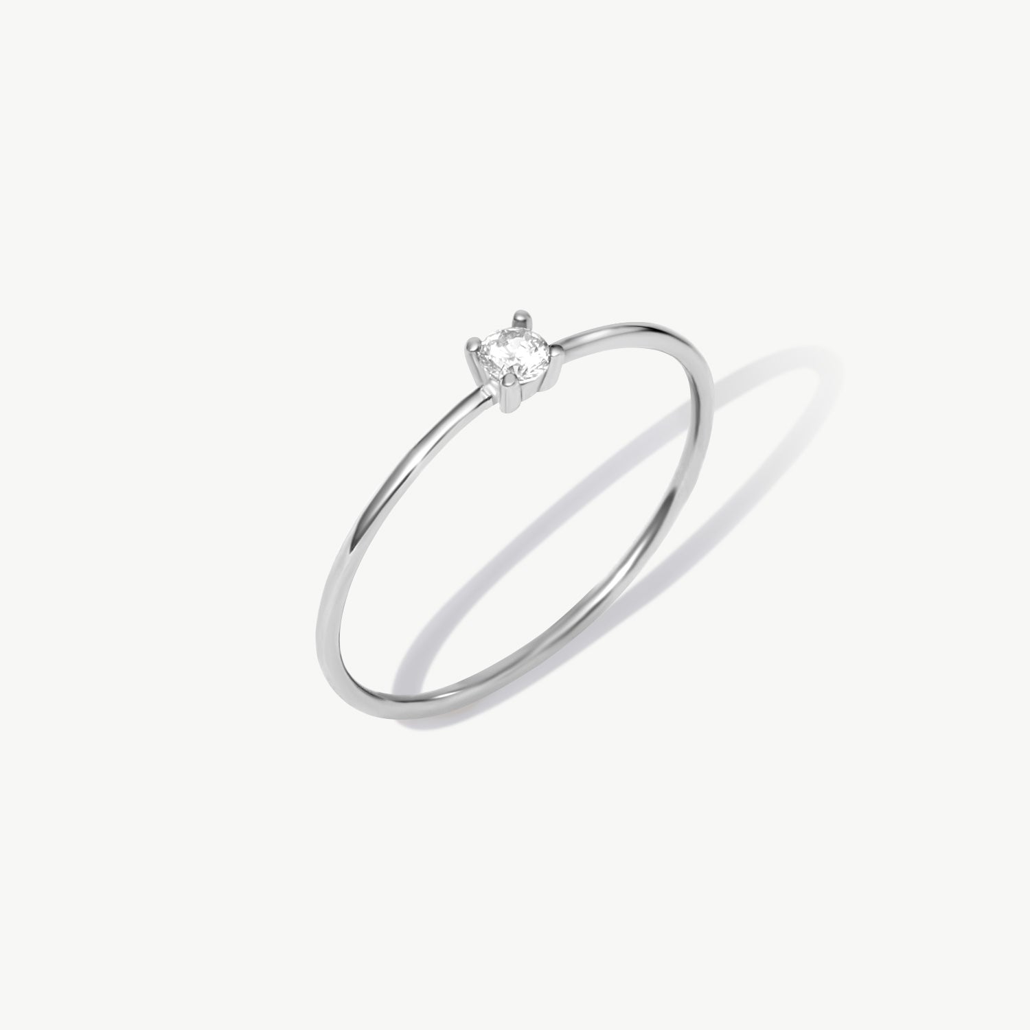 White gold solitaire ring featuring a natural round diamond in a timeless minimalist four-prong setting photographed on a clean white background.