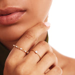 Editorial close-up of a woman wearing a dainty natural diamond solitaire ring crafted from genuine 14K solid gold with elegant minimalist styling.