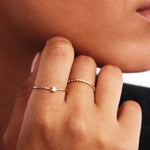 Lifestyle close-up portrait of a woman wearing a minimalist stackable wishbone engagement ring crafted from genuine 14K solid gold with natural diamond center stone.