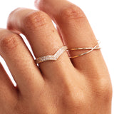 Close-up hand photograph featuring a pavé diamond wishbone stacking ring paired with a minimalist gold crossover ring.