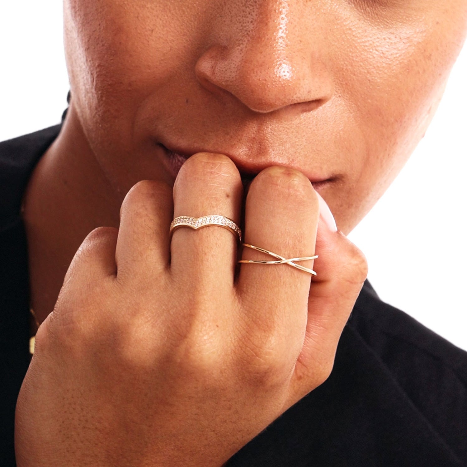 Editorial close-up portrait of a woman wearing a natural diamond V shaped eternity band paired with a minimalist 14K gold crossover ring.