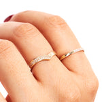 Editorial hand photograph featuring a natural diamond wishbone stacking ring styled with a minimalist polished gold band.