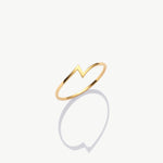 Minimalist yellow gold thunder bolt ring photographed upright on a white background with a soft shadow reflection.