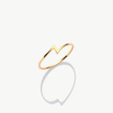 Minimalist yellow gold thunder bolt ring photographed upright on a white background with a soft shadow reflection.