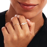 Editorial portrait of a woman wearing a minimalist lightning bolt ring crafted from genuine 14K solid gold styled with layered fine jewelry.