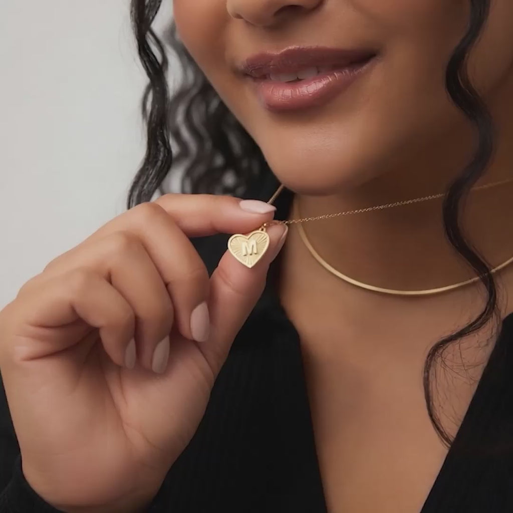 Luxury editorial video shot of a model wearing a handcrafted personalized initial heart pendant.